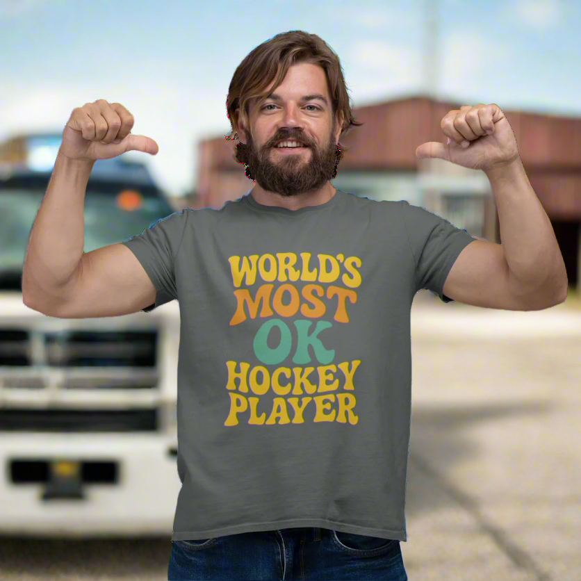 Man wearing a gray t-shirt with "World's Most OK Hockey Player" in a colorful, funky font