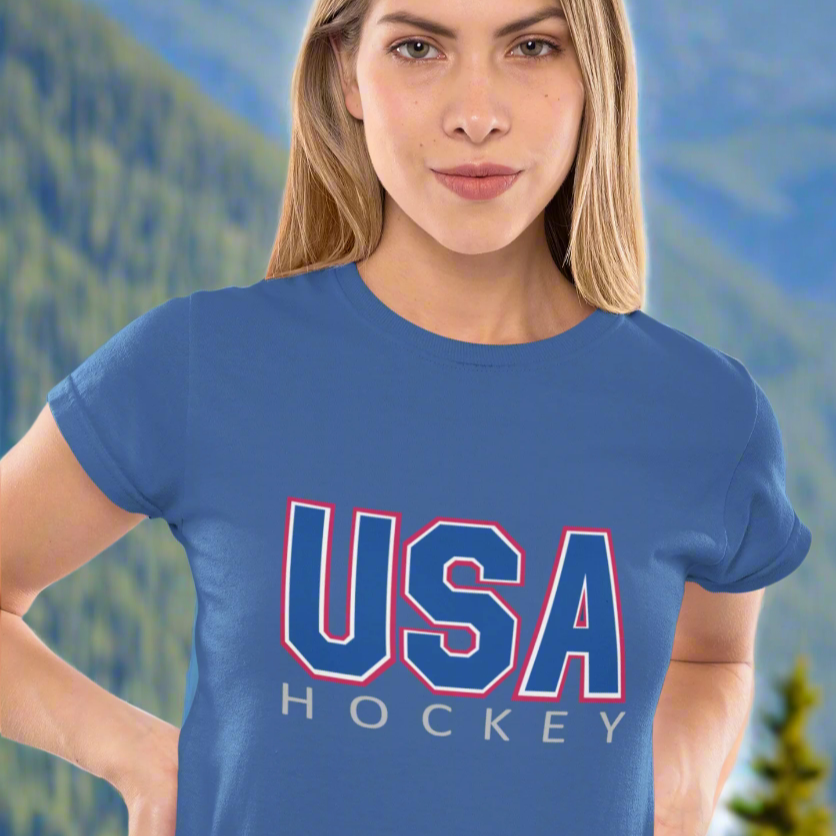 Woman wearing a blue 'USA Hockey' t-shirt against a Rocky Mountain background