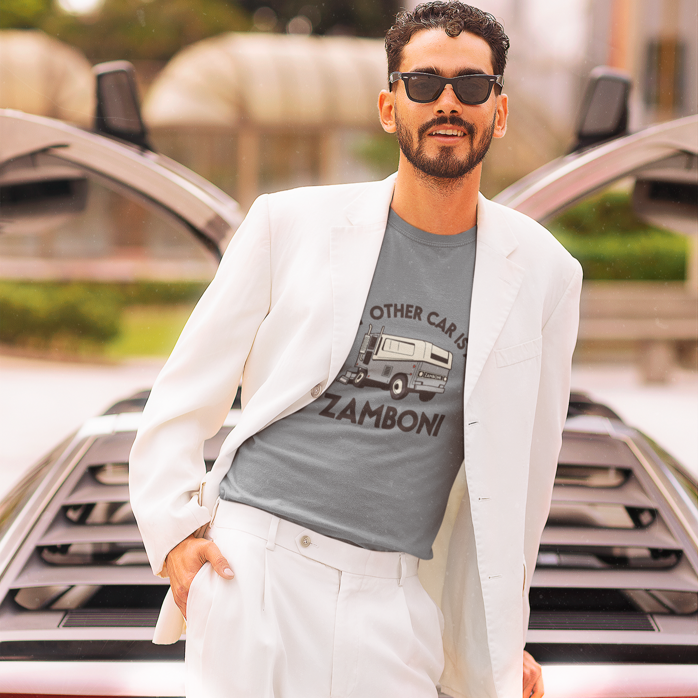 Man wearing sunglasses and a white blazer over a gray t-shirt standing in front of a Delorean. Funny design, and text reads, "My other car is a Zamboni"