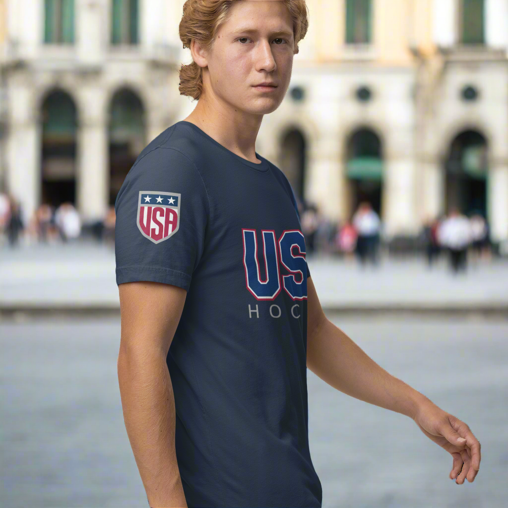A young man wearing a USA Hockey T-shirt with a USA shield on the shoulder and a bold USA hockey logo on the front